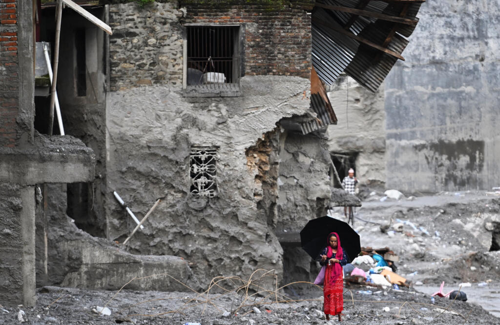 A woman walks among the ruins of flash floods in Nepal's Nuwakot district