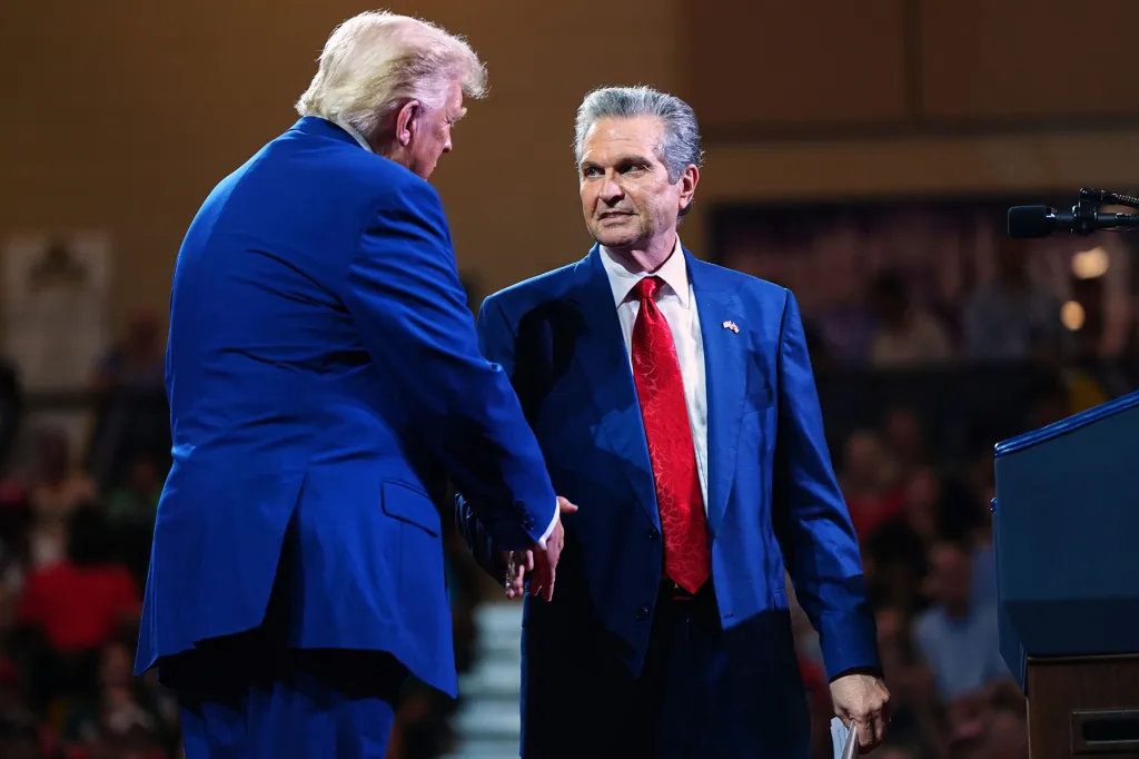 President Donald Trump shakes hands with Georgia Republican gubernatorial candidate Rick Jackson onstage at a political event.