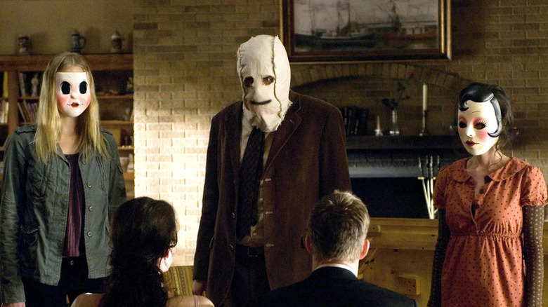 A trio of masked killers face a bound Kristen McKay (Liv Tyler) and James Hoyt (Scott Speedman) in The Strangers (2008)