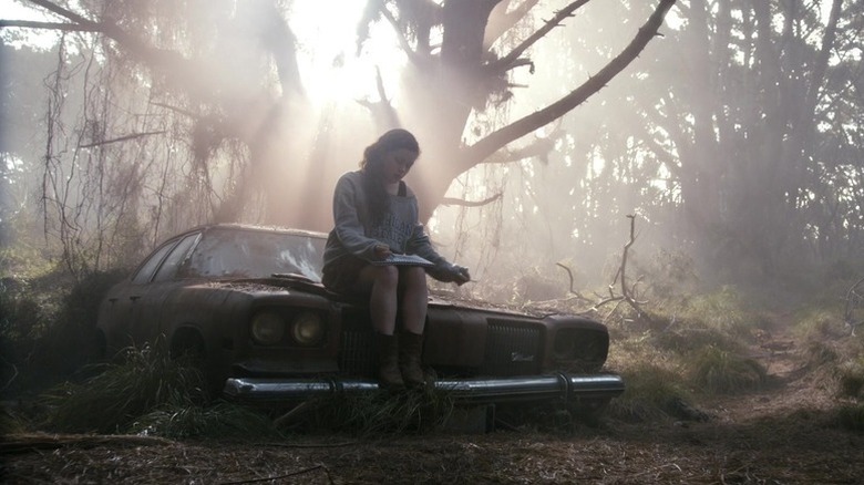 Mia Allen (Jane Levy) sits on an abandoned car in the woods in Evil Dead