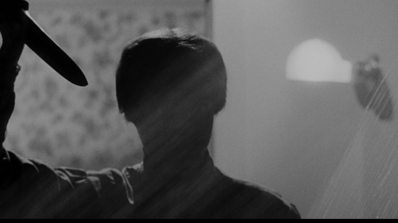 Anthony Perkins as Norman Bates in Psycho, seen in silhouette dressed as a woman and wielding a knife.