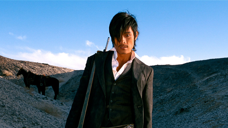 Lee Byung-hun as Park Chang-yi in The Good, The Bad, The Weird, standing against a hilly backdrop with horses behind him.