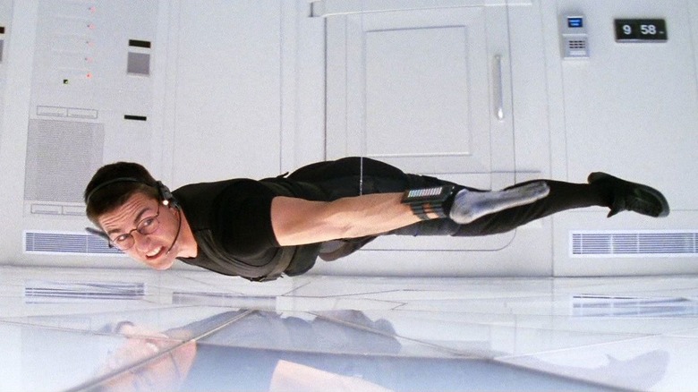 Tom Cruise as Ethan Hunt in Mission: Impossible, hovering just over the floor from a wire in a stark white room.