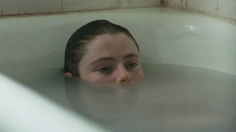 Thomasin McKenzie's Eileen sits in a bath with her eyes above water in Eileen