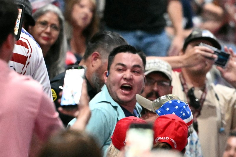 A protester (C) is detained by a Sheriff deputy as US President Donald Trump speaks during a campaign rally at the Freeman Coliseum in San Antonio, Texas, on October 7, 2026. Republican Senate candidate Ken Paxton is in a close race with Democratic candidate James Talarico for one of Texas' US Senate seats. (Photo by Mandel NGAN / AFP via Getty Images)