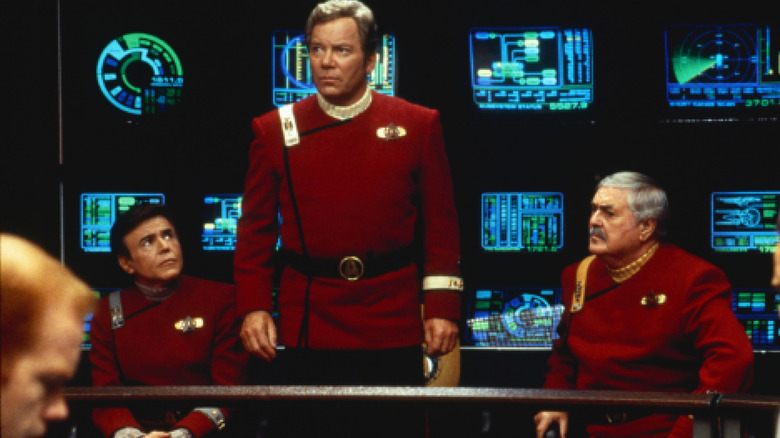 Walter Koenig as Pavel Chekov and James Doohan as Montgomery Scott sitting in between William Shatner as James Kirk on the bridge of a starship in Star Trek: Generations